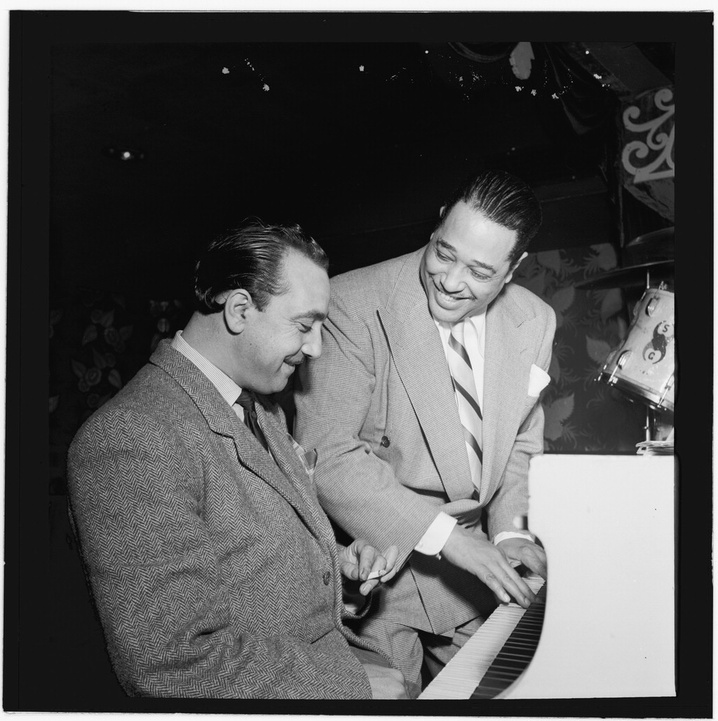 Django Reinhardt seated at a piano beside Duke Ellington at the Aquarium in New York.