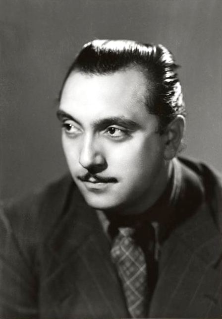 Django Reinhardt in a dark suit and patterned tie, looking to the side in a Studio Harcourt portrait.