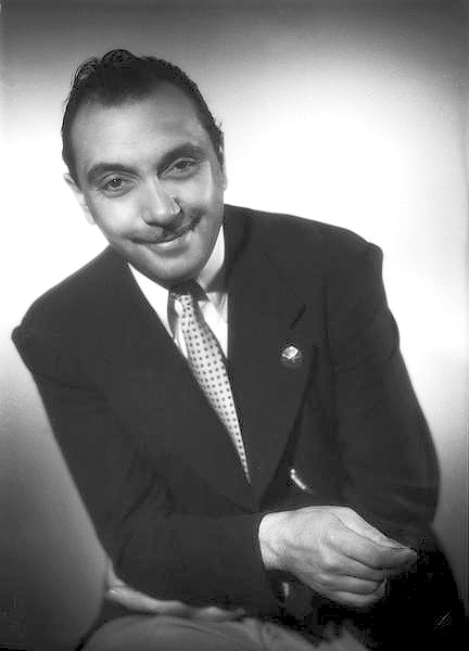 Django Reinhardt seated with his hands together in a Studio Harcourt portrait.